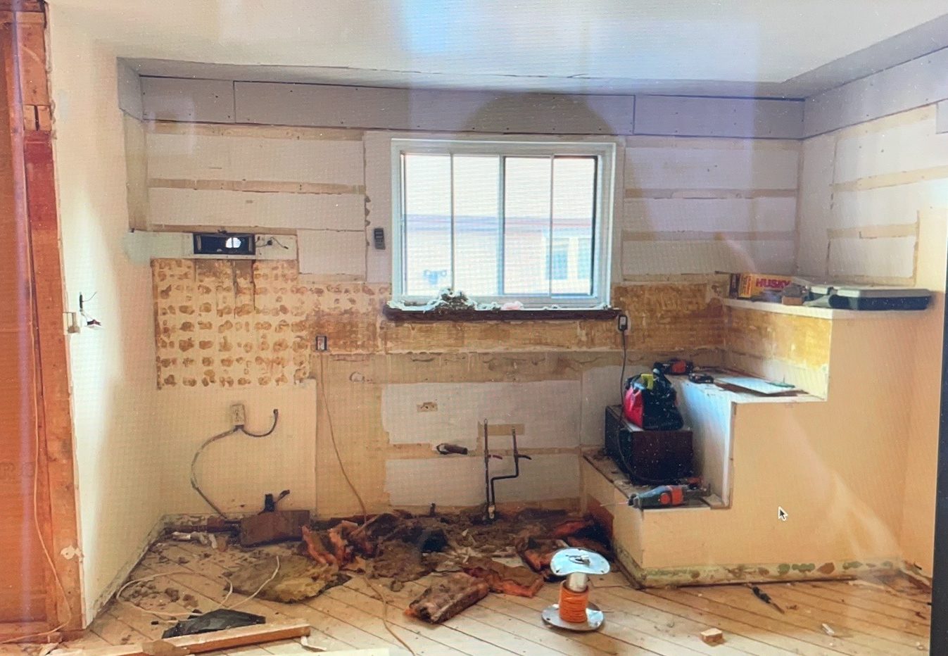Kitchen before: gutted, with the stair bulkhead on the right