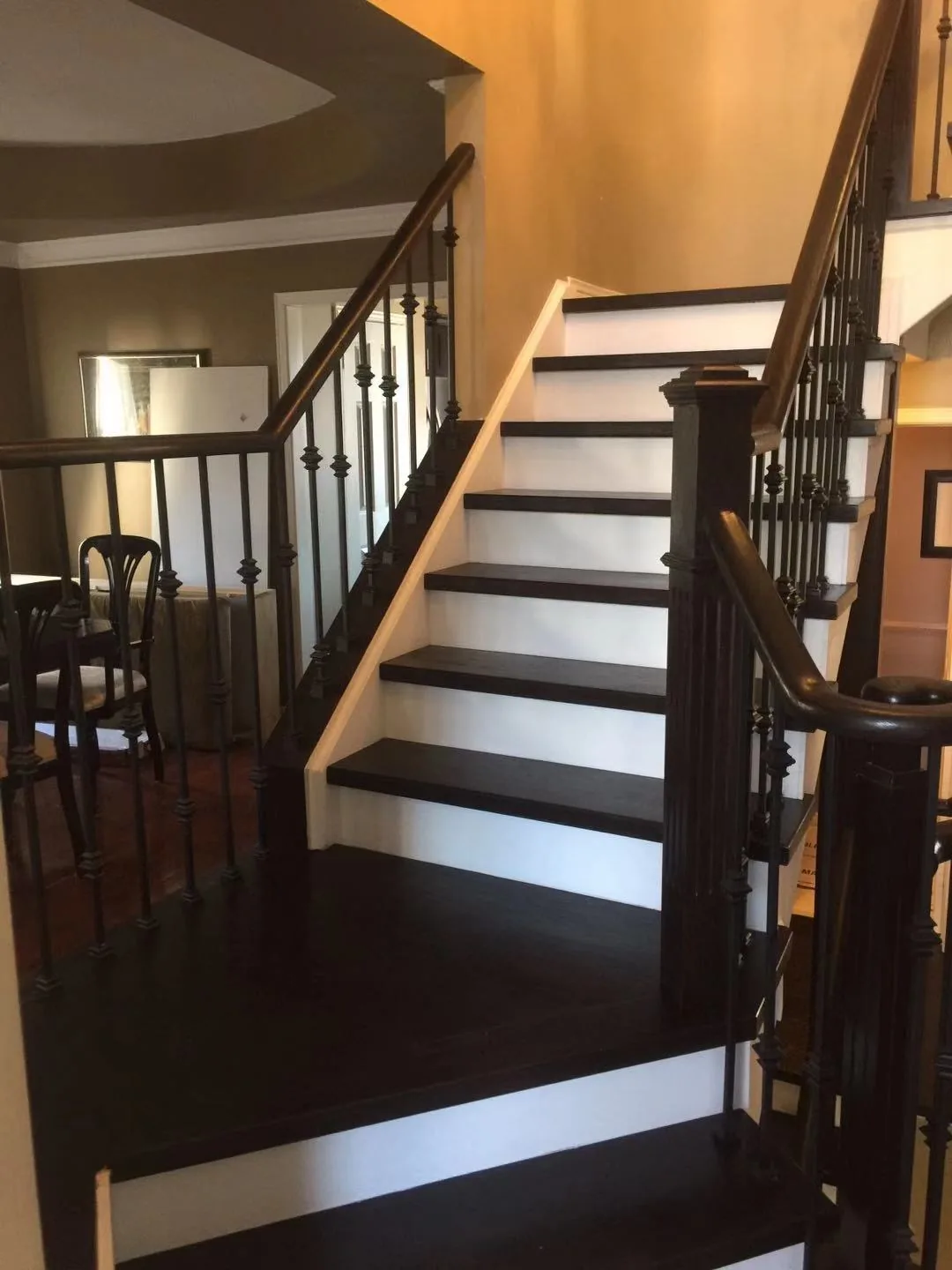 Dark-stained wood stair treads with white risers and black iron balusters, stair renovation in Oakville, ON